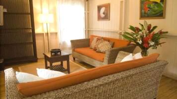 A living room with a sofa, a small table, a lamp, and a painting on the wall.