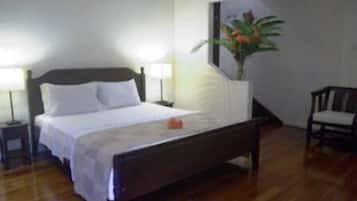 A neatly made bed with white linens, a bedside lamp, and a nightstand.