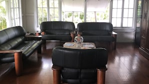Amplia sala de estar con un gran ventanal, un sofá de cuero negro, una mesa de centro y un aparador de madera.