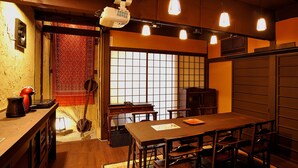 A traditional Japanese room with tatami flooring, a low wooden table, and a sliding door. - Theatre and Library Residence -Kyoto Imagumano- (Kyoto)