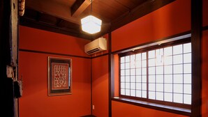 A room with a traditional Japanese aesthetic, featuring tatami flooring, a low wooden table, a shoji screen window, and a framed artwork on the wall. - Theatre and Library Residence -Kyoto Imagumano- (Kyoto)