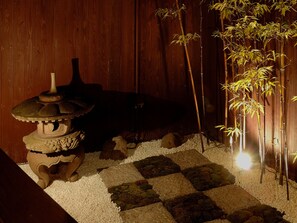 A traditional Japanese garden with a stone lantern, bamboo, and a wooden backdrop. - Theatre and Library Residence -Kyoto Imagumano- (Kyoto)