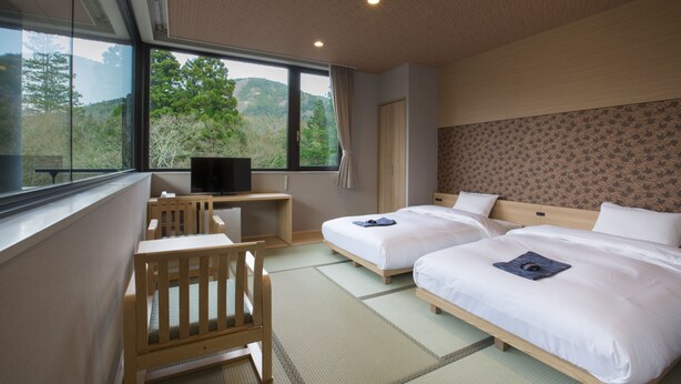 Una habitación de hotel con dos camas, un escritorio, una silla y un televisor.