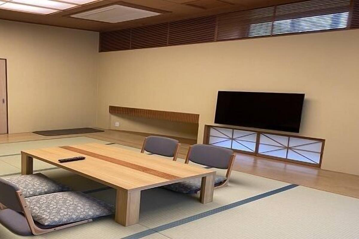 Una sala de conferències amb taula de fusta, quatre cadires, estris de tatami, televisió i una porta corredissa.