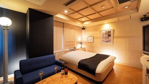 A hotel room with a bed, a sofa, a table with two bottles of wine, and a TV. - Hotel Saint Martin – Adults Only (Kyoto)
