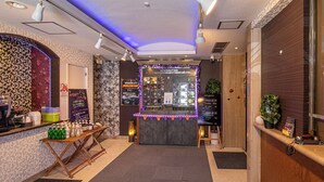 A hotel reception area with a counter, a coffee machine, a plant, and a signboard. - Hotel Saint Martin – Adults Only (Kyoto)