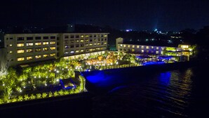 A hotel with multiple floors, a courtyard with water features, and a view of the surrounding cityscape. - Hotel Nampuro (Shimabara)