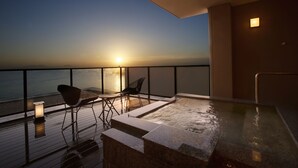 A rooftop terrace with a hot tub, seating area, and a view of the ocean at sunset. - Hotel Nampuro (Shimabara)