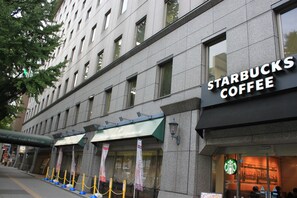 A building with a Starbucks Coffee sign, a green awning, and a sign for a hotel. - Hotel Grand Terrace Sendai Kokubuncho (Sendai)