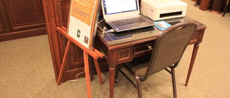 Un bureau en bois avec un ordinateur portable, une imprimante et un document encadré.
