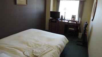 A hotel room with a large bed, a desk with a computer, a chair, and a television.