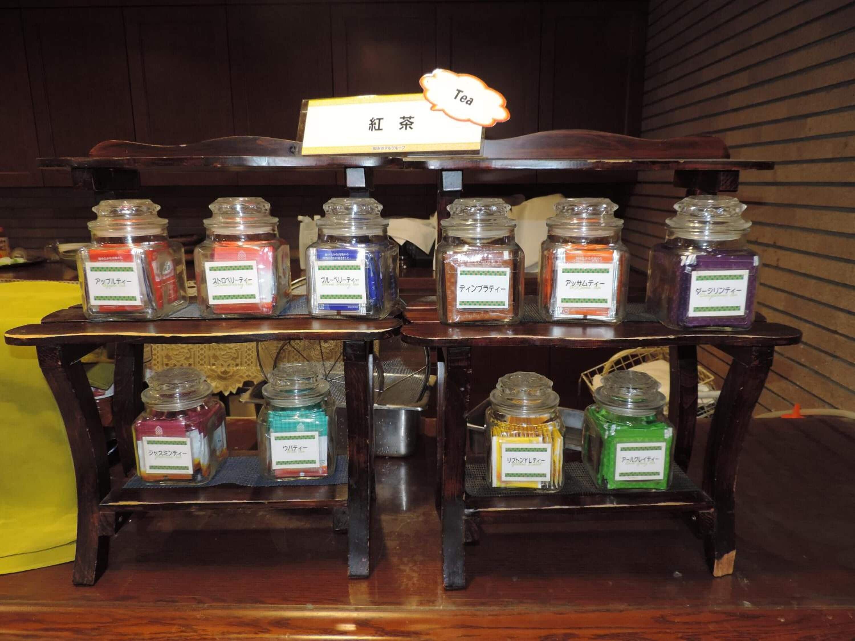 A display of various tea flavors in glass jars on wooden stands.