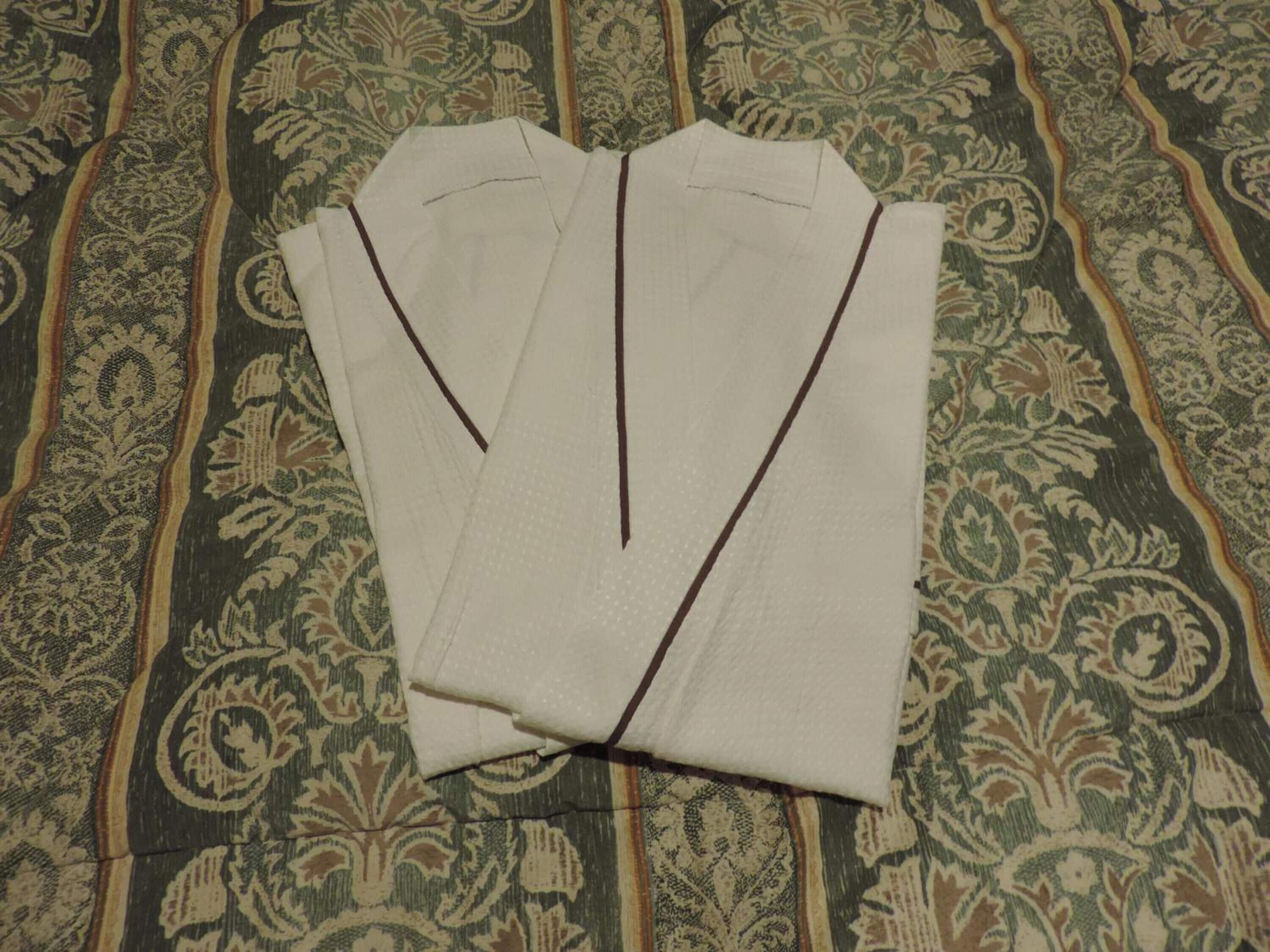 Una camisa blanca impecablemente doblada con detalles oscuros sobre un fondo de tela estampada.
