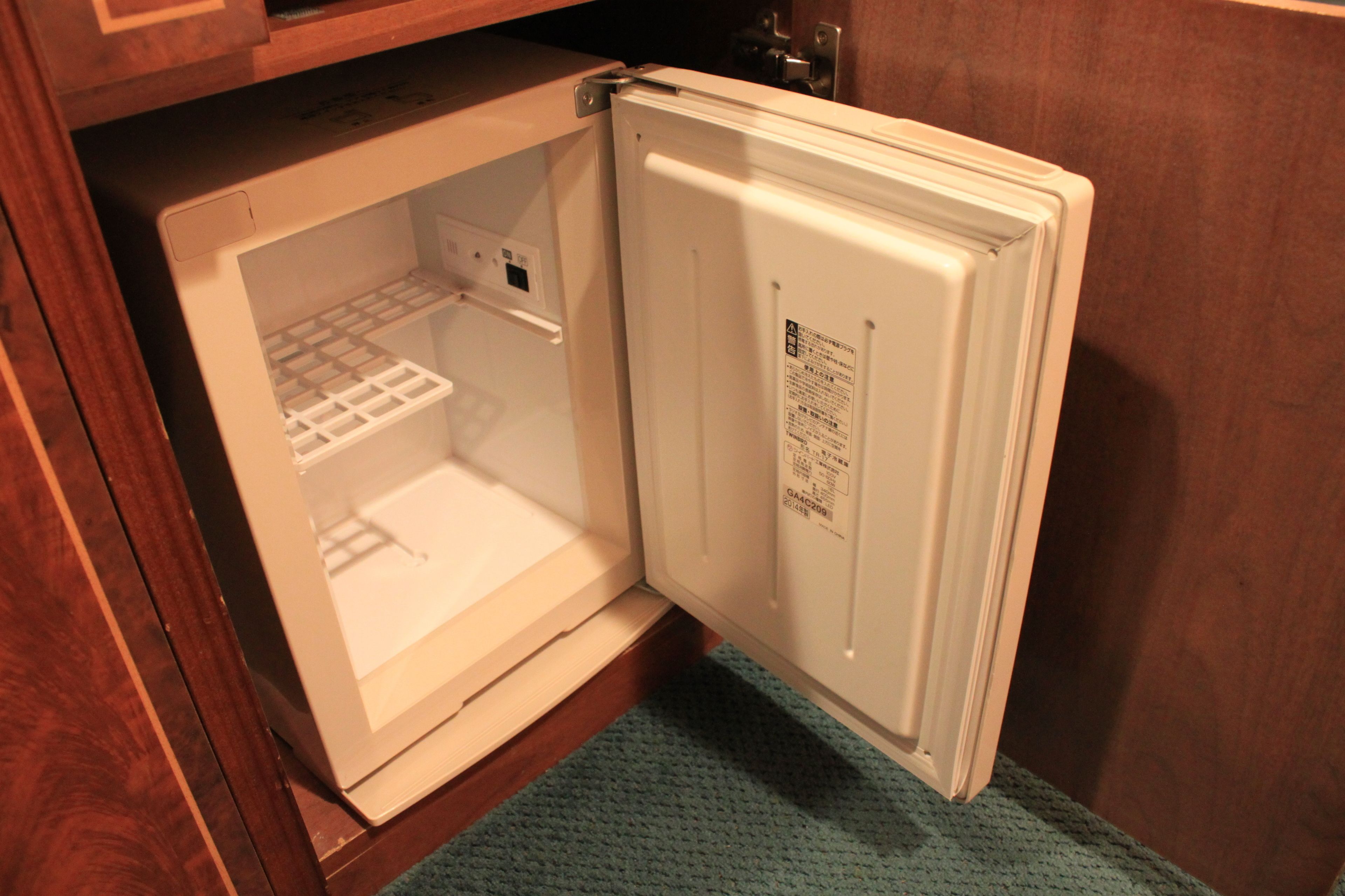 Un réfrigérateur ouvert, avec une armoire en bois au-dessus.