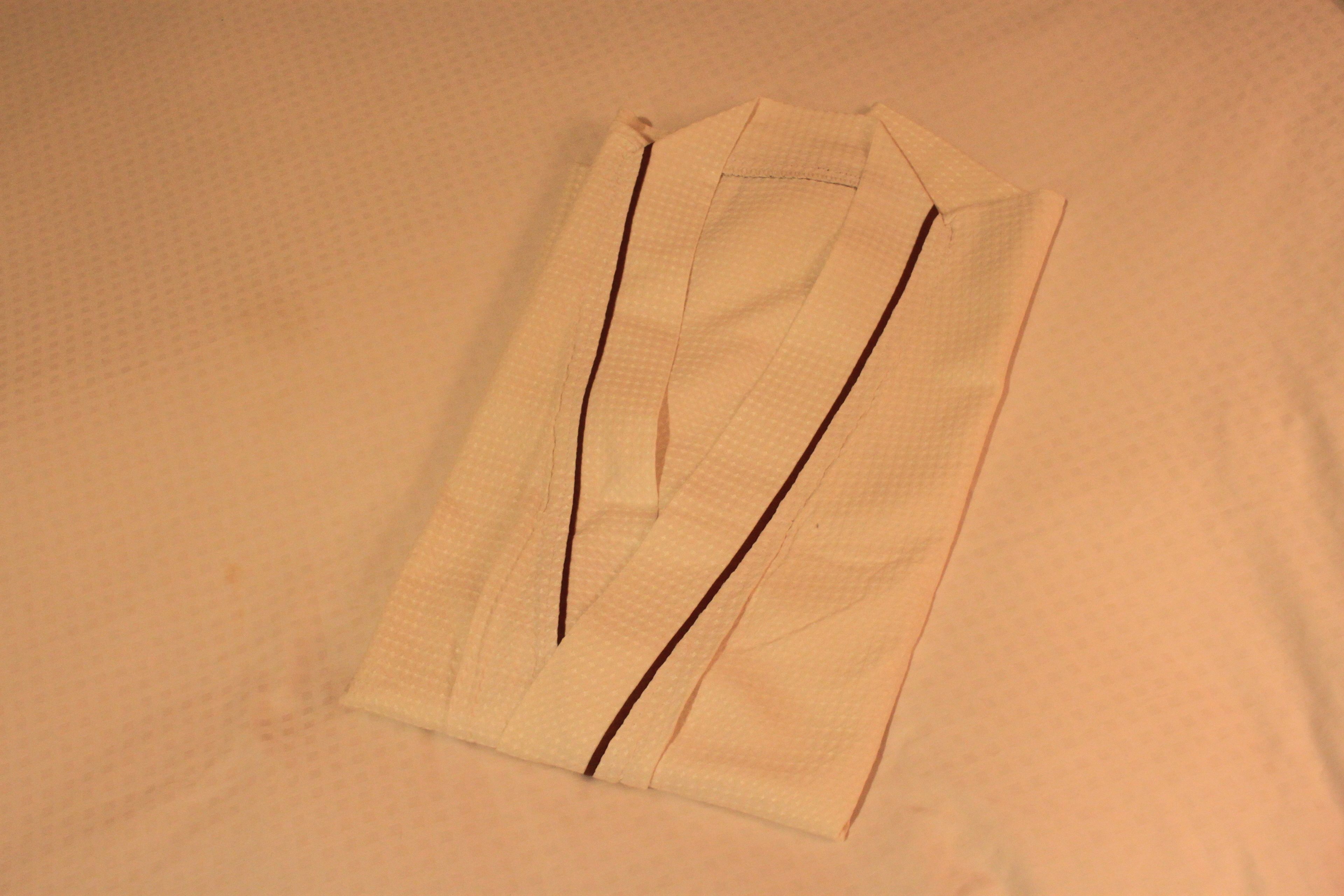 A neatly folded white shirt with dark stripes on a plain background.