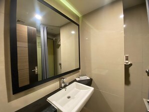 A modern bathroom with a large mirror, a white sink, and a shower area. - Atlantic City Hotel (Bandung)