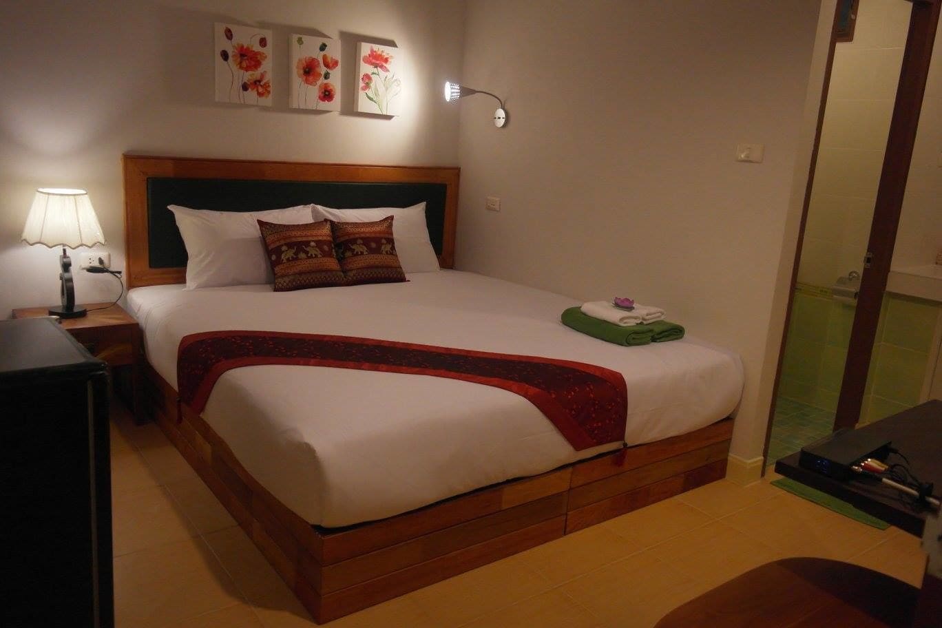 A neatly made bed with a wooden headboard, a bedside lamp, and a small table with a lamp.