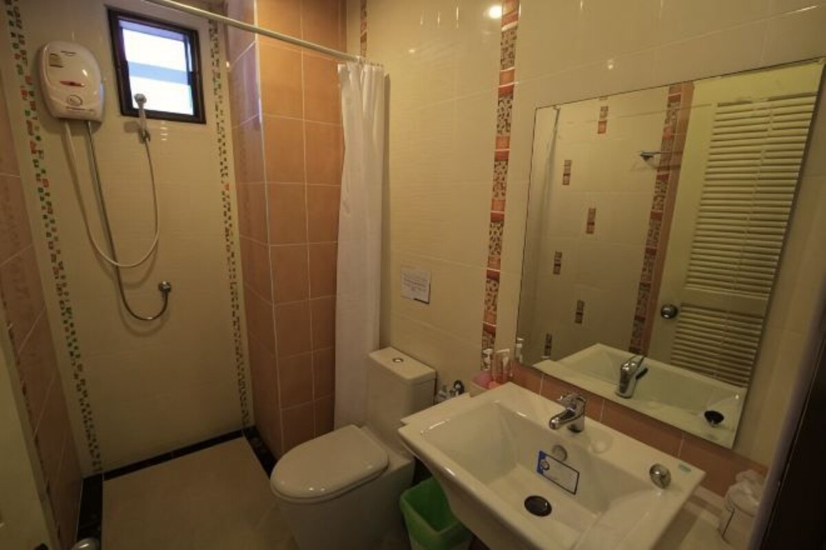Un baño con inodoro, lavamanos, espejo y ducha.