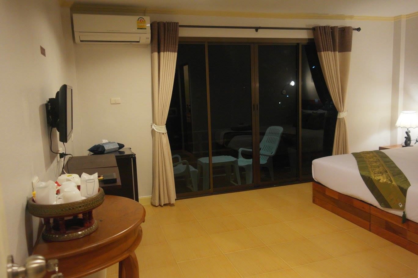 Habitación de hotel con cama, escritorio con computadora, silla y mesa con una bandeja de objetos.