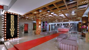 Un hallo espacioso con alfombra roja, una zona de recepción con mostrador y un letrero iluminado grande que dice "BROADWAY".