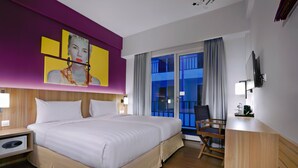 Habitación de hotel con una cama grande, un escritorio, una silla, un balcón con vistas y un cuadro en la pared.