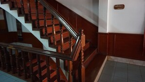 A wooden staircase with a handrail, a sign on the wall, and a tiled floor. - Champa Hotel (Pakse)