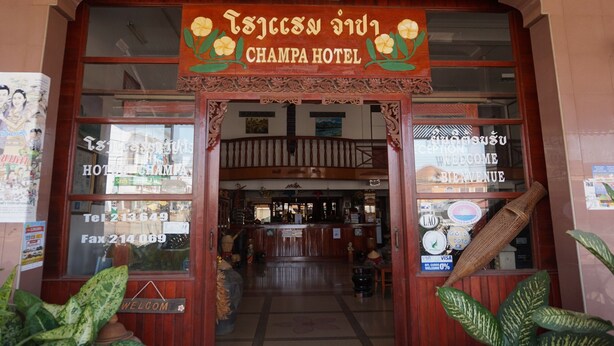 The entrance of Champa Hotel with a wooden facade, a reception desk, and a signboard displaying the hotel's name. - Champa Hotel (Pakse)
