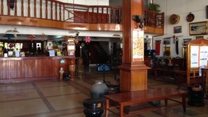 A spacious lobby with a wooden reception desk, a staircase, and a seating area. - Champa Hotel (Pakse)