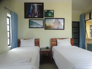 Une chambre d’hôtel avec deux lits, une table de chevet et un mur orné de tableaux.