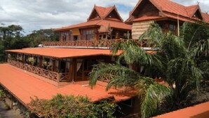 A traditional wooden building with a red-tiled roof and a balcony. - Mekong Paradise Resort (Pakse)