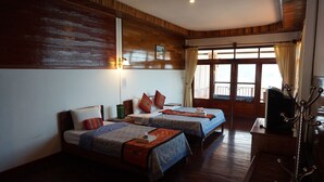 A hotel room with two beds, wooden walls, a window with curtains, and a wooden floor. - Mekong Paradise Resort (Pakse)