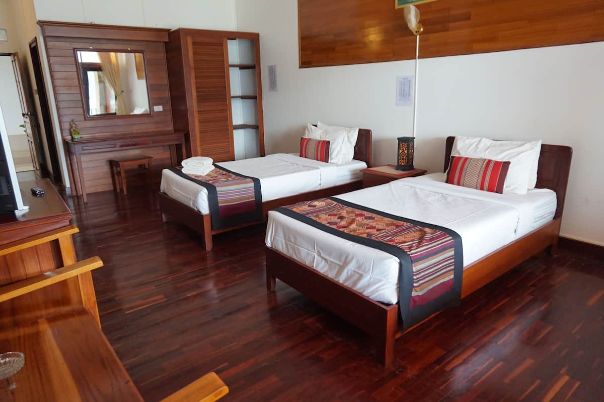 A hotel room with two wooden beds, a wooden desk, and a mirror above the desk.