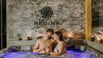 Relax in a hot tub surrounded by a serene stone wall, perfect for a romantic escape.