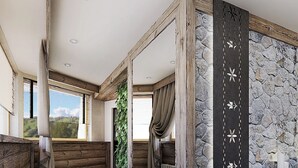 Et moderne spa-rum med stenvæg, træbjælker, et stort spejl og et siddeområde med massagestol.