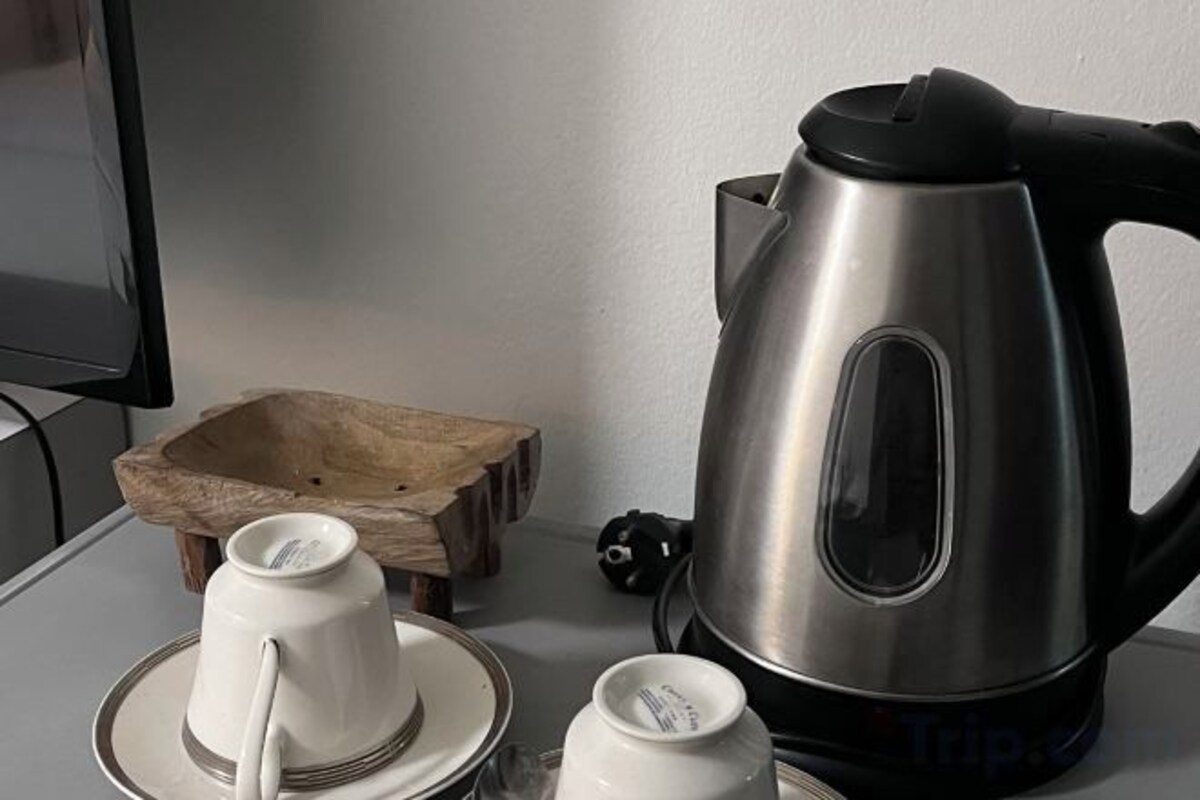 Una tetera d'acer inoxidable, un safata de fusta i tasses blanques damunt d'una taula.