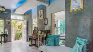 Una habitación con una cama de metal blanco, almohadas azul turquesa y un cuadro en la pared.