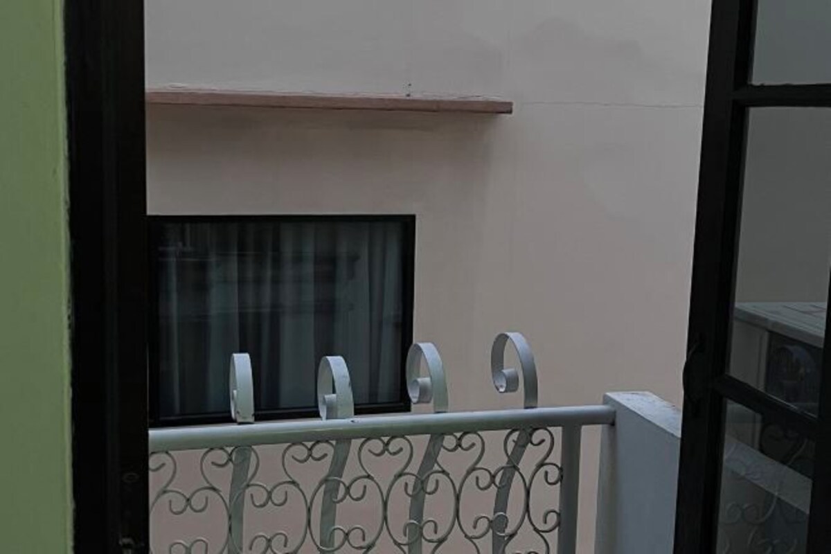 Un balcon avec une balustrade en métal et une fenêtre avec un rideau.