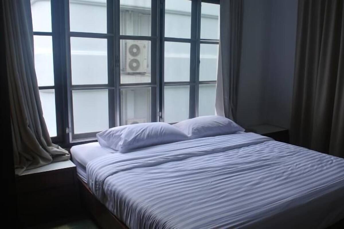 Un dormitorio con cama, ventana y cortinas.