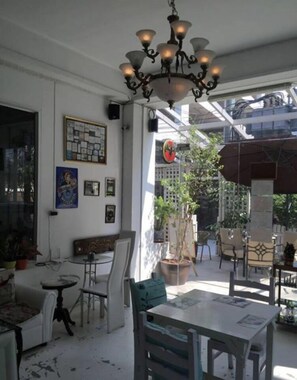 A dining area with a chandelier, tables, chairs, and a view of the outside.