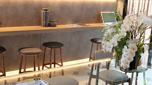 Eine moderne Bar mit Hockern, einer Zeitschrift auf dem Tisch und Zimmerpflanzen.