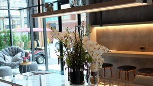 Ein modernes Interieur mit einem Glastisch, Holzstühlen und einer Vase mit weißen Blumen.