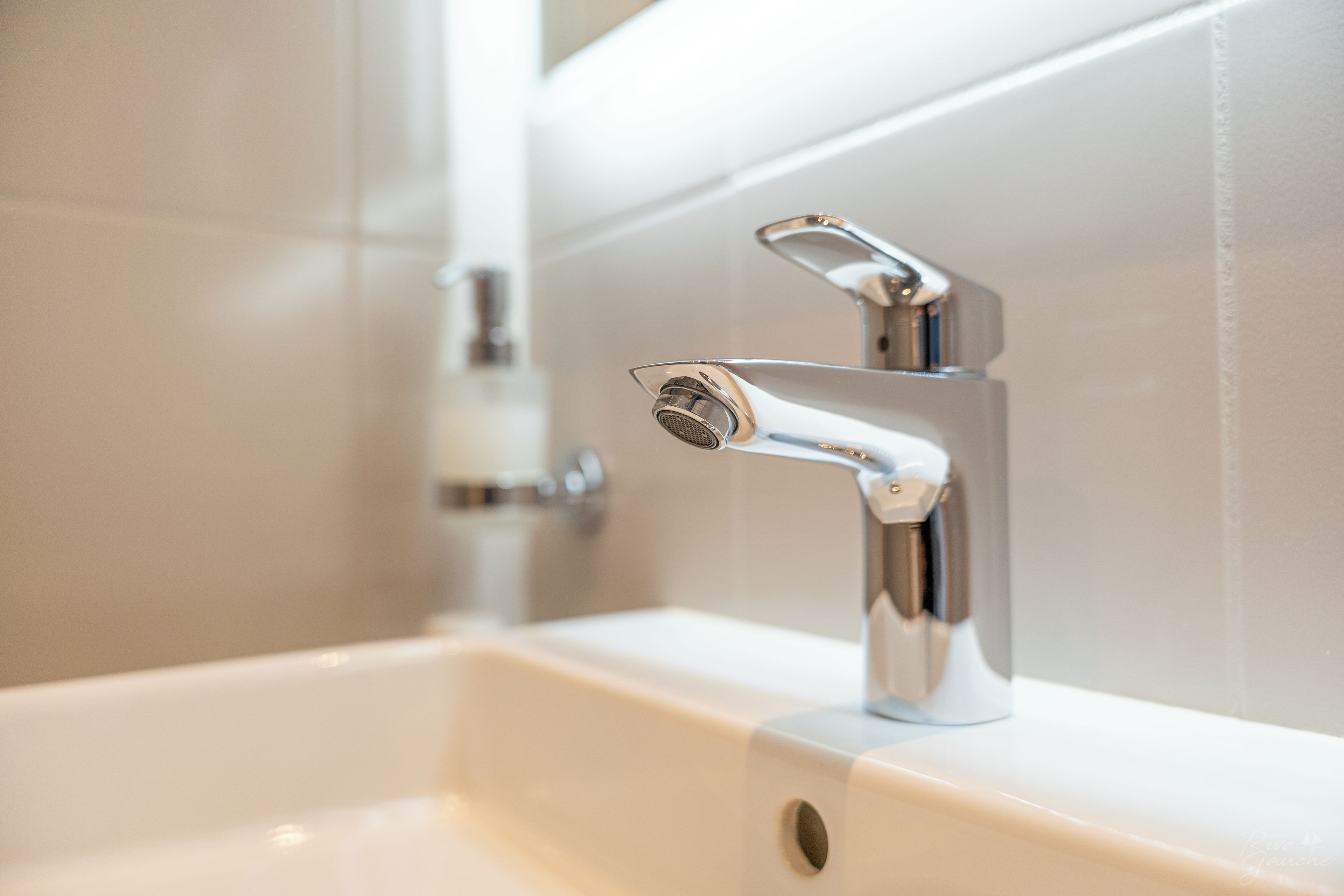 A bathroom sink with a chrome faucet and a mirror.
