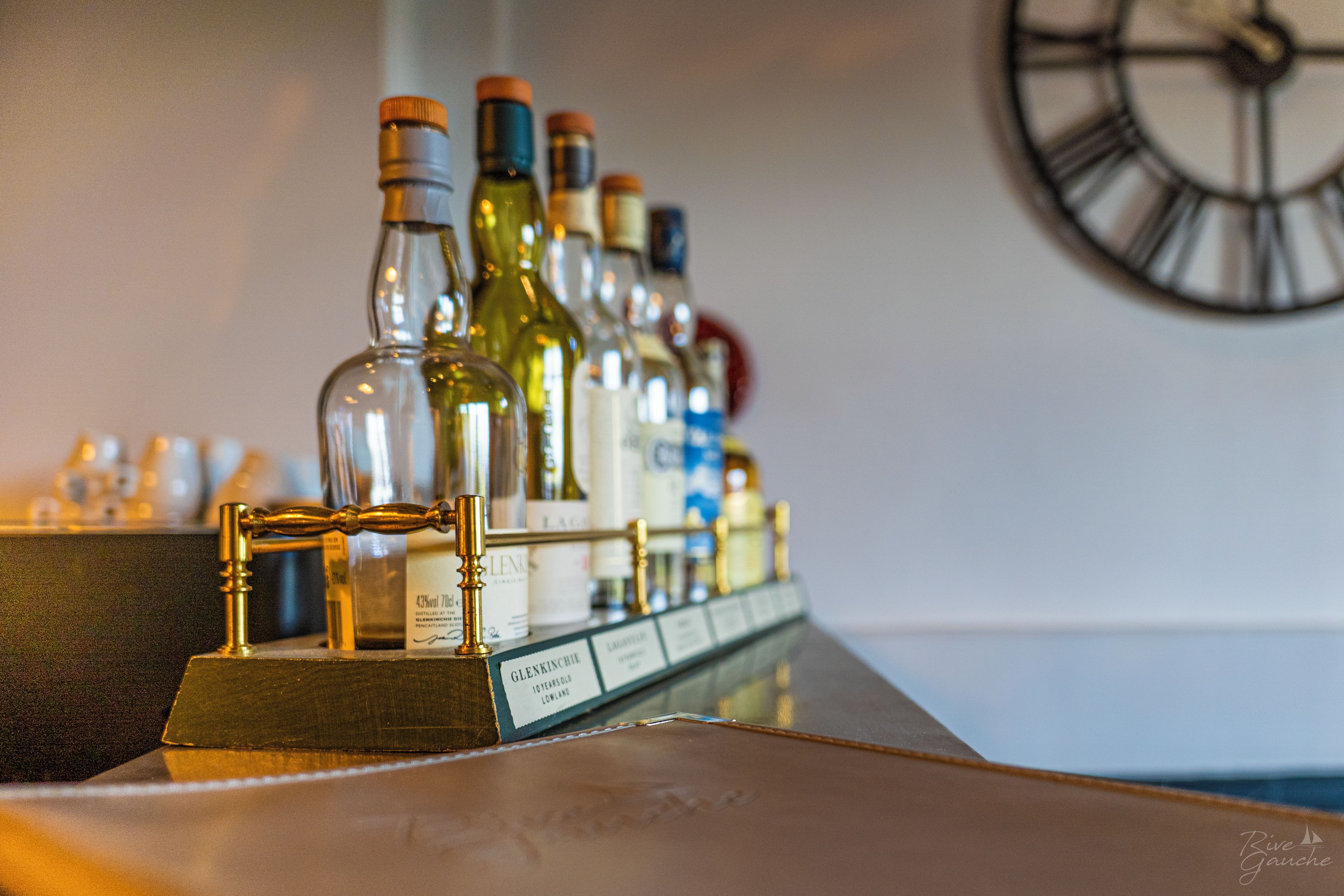 Zona de bar con una variedad de botellas de licor y un reloj en la pared.