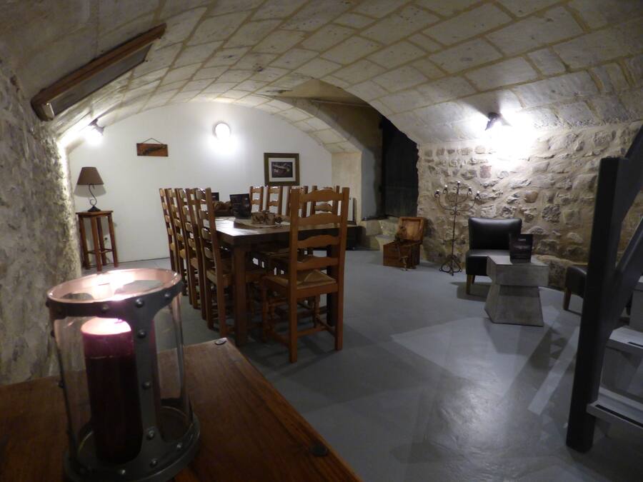 A dining area with a stone wall, wooden chairs, a table, and a candelabra.