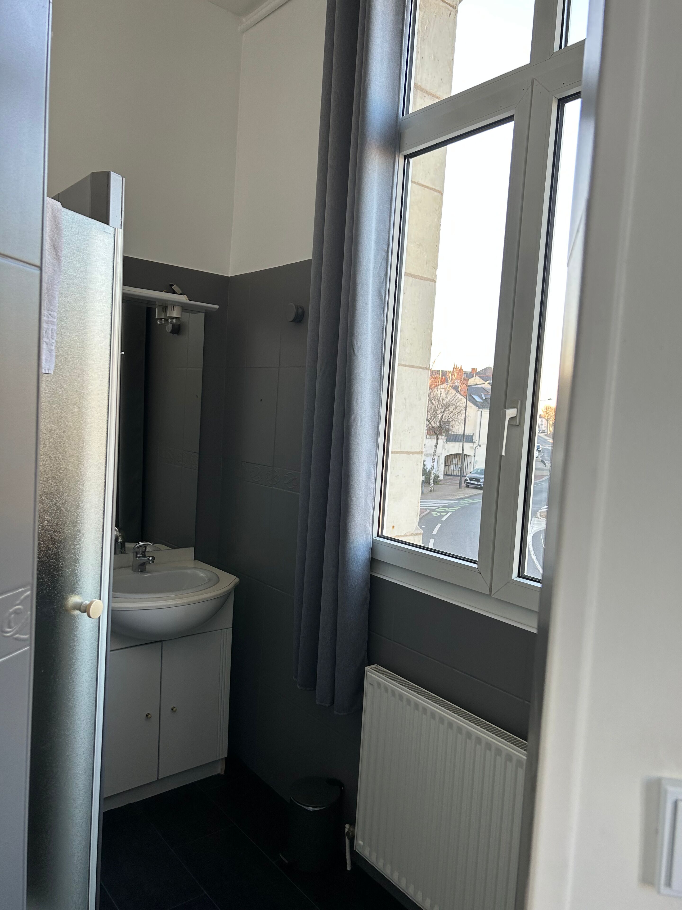 Ein kleines Badezimmer mit Waschbecken, Spiegel und Fenster.