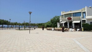 A paved walkway with a restaurant and outdoor seating area. - Nauticus Hotel Ugento (Ugento)