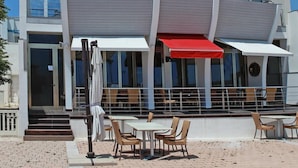 A modern multi-story building with a flat roof, large windows, and outdoor seating with umbrellas. - Nauticus Hotel Ugento (Ugento)