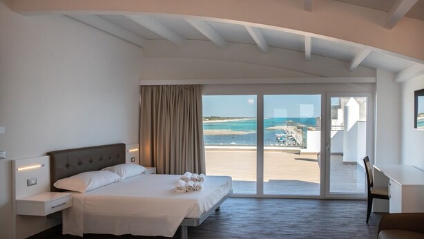 A hotel room with a bed, a desk, and a view of the sea. - Nauticus Hotel Ugento (Ugento)