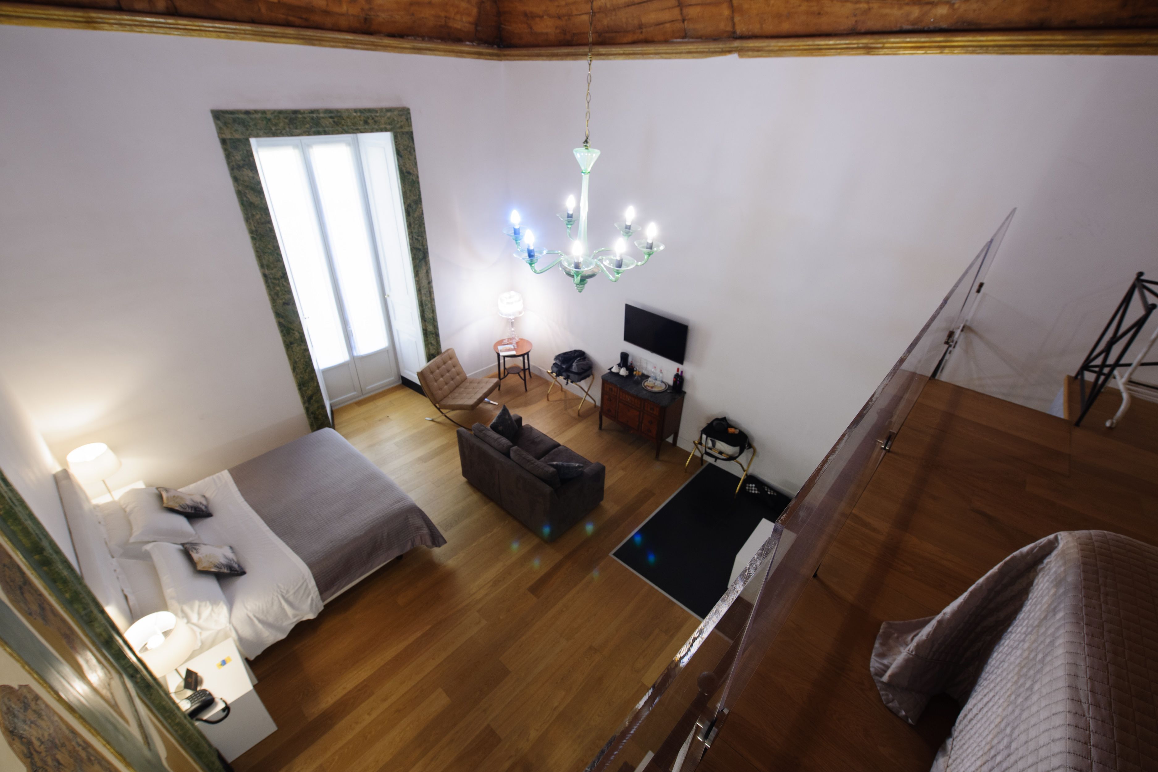A spacious room with a bed, a sofa, a TV, and a chandelier.