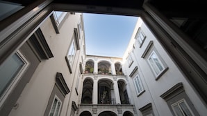 Vista a través de una ventana abierta de un edificio con varios balcones y ventanas de arco.